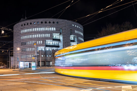 Yellow tram passing modern office building at night in Basel Switzerland