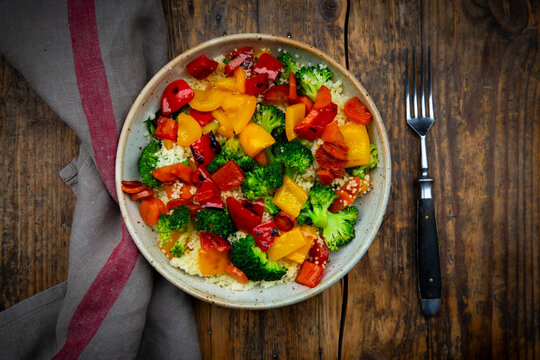 Colorful couscous bowl with grilled vegetables on rustic wood table