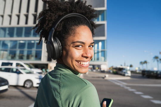 Smiling woman with headphones outdoors in urban setting