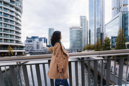 Businesswoman walking on city bridge with skyscrapers in background