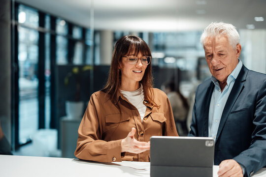 Business colleagues collaborating with tablet in modern office