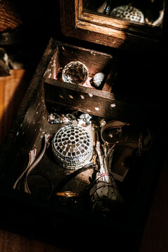 Ornamental box with shiny objects and mirror in dim wooden setting