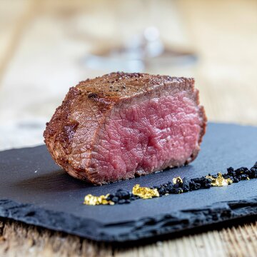 Steak saignant coup&eacute; pos&eacute; sur ardoise avec sel et poivre