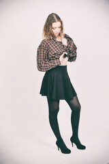 Naklejka premium Blondes Model im Outfit mit Rock und Strumpfhose, nachdenkliche Pose, modernes Fashion- und Lifestyle-Porträt im Studio isoliert