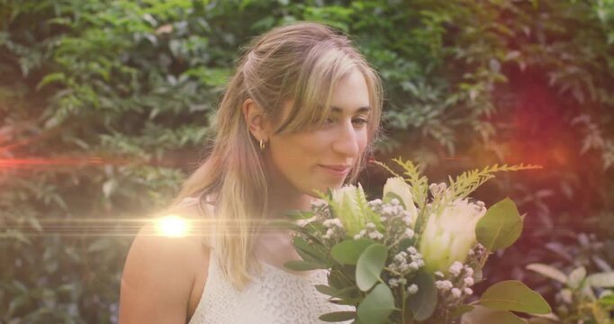 Woman holding bouquet inhaling, lifting gaze and smiling with flare overlays growing for wedding