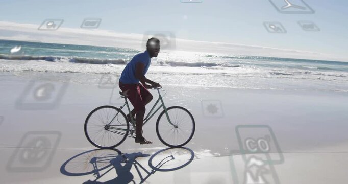 Cam tracking man riding bike along wet shore blue-shirt red-shorts barefoot for leisure with icons