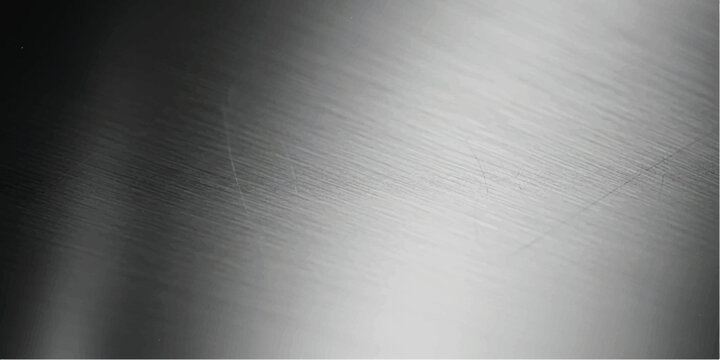 Close up view of brushed metal surface with diagonal light reflection and dark shadows on the left side showing fine linear texture and metallic grain