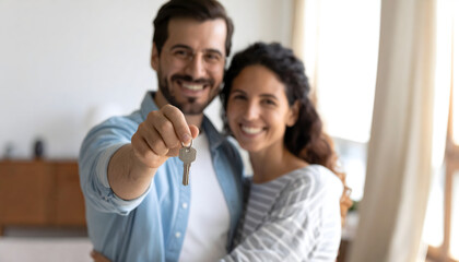 Obraz premium Dream Home Unveiled: A smiling couple, illuminated by natural light, joyfully presents the key to their dream home, signifying a fresh start and the culmination of their aspirations. 