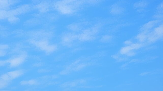 A blue sky timelapse video footage with soft stratocumulus clouds gently drifting across a clear azure sky, creating a peaceful, airy atmosphere with smooth motion and natural daylight ambiance. 4k.
