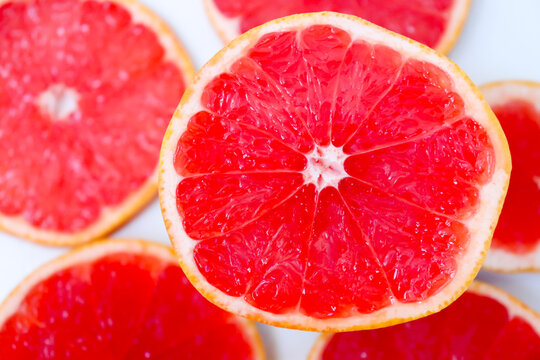 Freshly cut grapefruit slices isolated on a white background, bright pink or red citrus fruit pieces with juicy texture, healthy natural food concept.