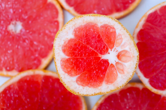 Freshly cut grapefruit slices isolated on a white background, bright pink or red citrus fruit pieces with juicy texture, healthy natural food concept.