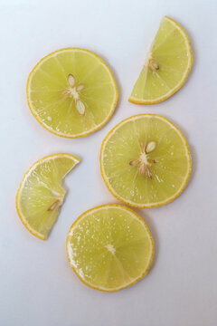 Freshly cut lemon slices isolated on a white background, bright green citrus fruit pieces with juicy texture, healthy natural food concept.