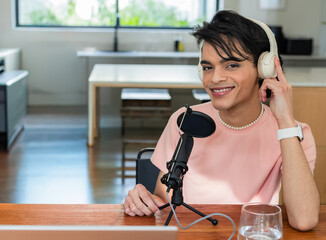 Male content creator recording podcast at home kitchen table with microphone and laptop, copy space © wavebreak3