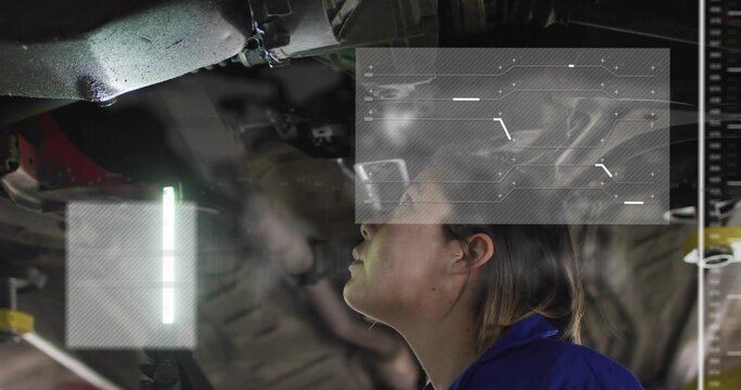 Inspecting female technician in blue coverall examining lifted vehicle chassis at garage, LED HUD