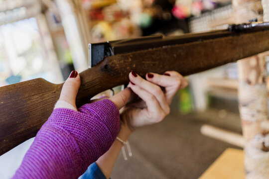 Woman with purple cast shooting at a fair game in summer