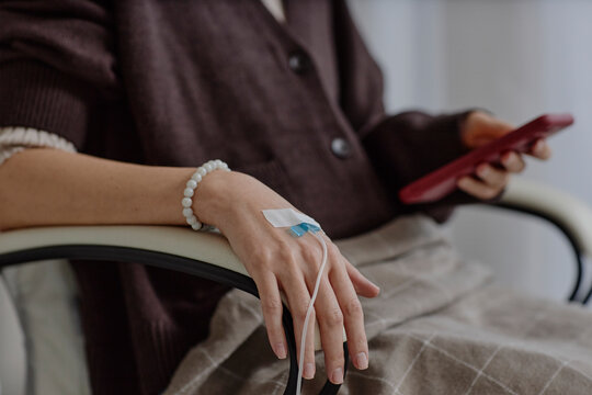 Patient receiving IV therapy while using smartphone in clinic