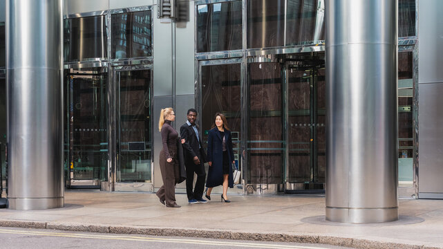 Business team walking together outside modern office building