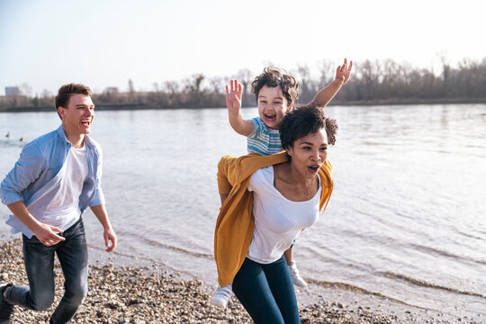 Family having fun running together by a river on the beach