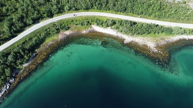 Cinematic top down view of car driving along scenic coastal road in Norway