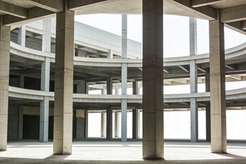Naklejka premium Modern concrete structure with repeating columns and circular levels under construction