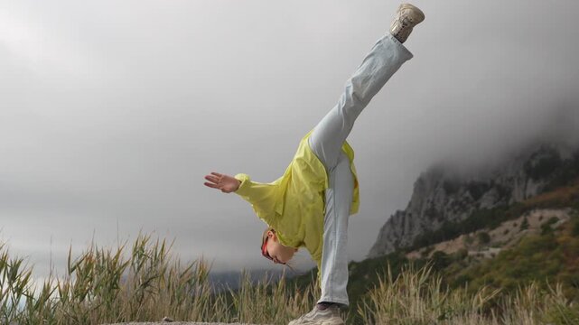 Dancer stretching mountains high flexible young girl balances against foggy nature landscape.