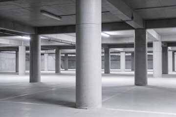 Obraz premium Vast concrete parking garage interior with rows of columns and overhead lighting