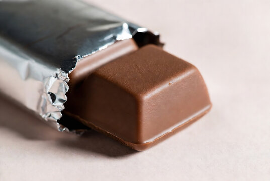 A single Hershey&rsquo;s chocolate bar is partially unwrapped on a light-colored surface.
