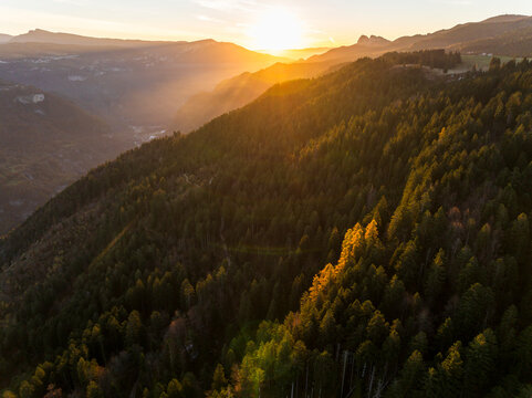 Landscape, travel. Aerial view of forest and mountains at sunset, sun rays shining through trees, destination concept. First World war,Cherle Fort,Trentino,Italy