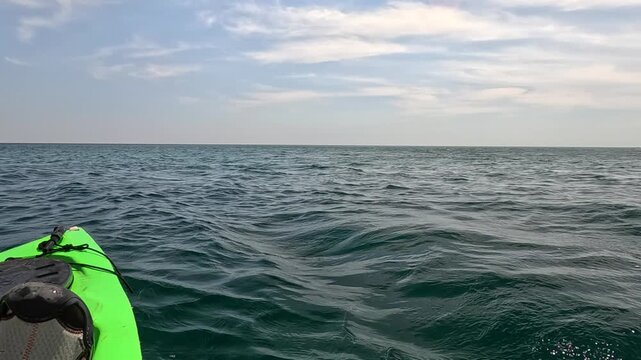 Kayaking ocean adventure featuring a first person perspective of rowing a green kayak through calm sea waters near scenic rocky cliffs