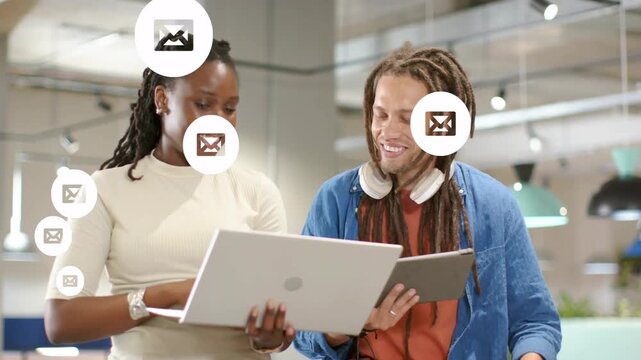 Woman tapping laptop working, man pointing, causing message icons floating covering tablet in tech