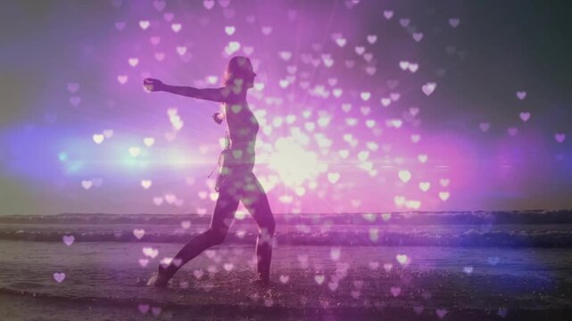 Woman dancing on shoreline, stepping forward and activating heart bokeh and purple flare for ads