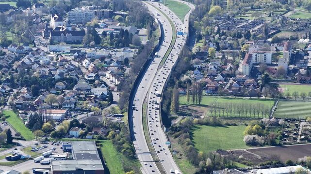 Aerial view of a highway cutting through the landscape, with cars flowing in both directions near buildings, Sausheim, Grand Est, France.