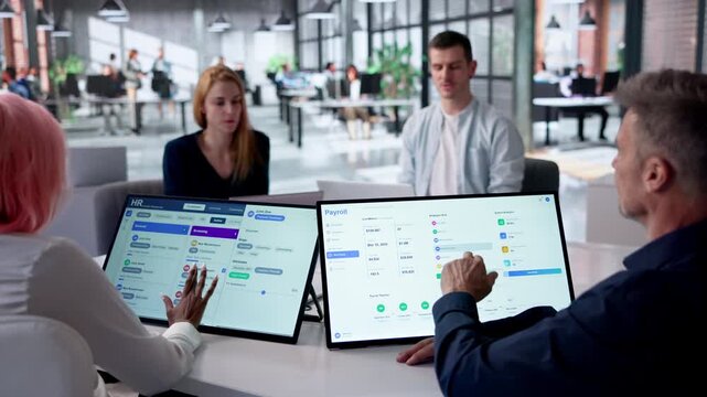 HR Manager Reviews Payroll Software On Tablet During Team Meeting