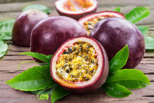 Passion fruits and cross section of passion fruit with pulpy juice filled with seeds.