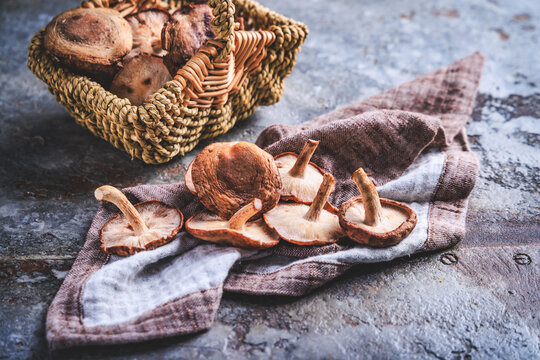 Freshly harvested shiitake mushrooms in woven wicker basket on rustic wooden table