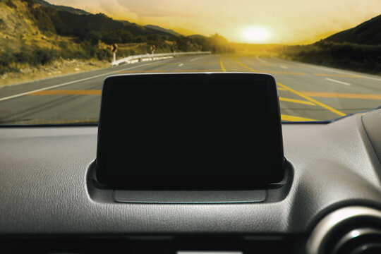 Car Dashboard Blank Screen on Road Trip, A blank infotainment screen on a car dashboard with a scenic highway view at sunset.