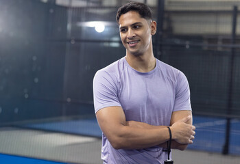 Indian man late twenties standing on blue racquet court wearing purple sport tee showing wristband © wavebreak3