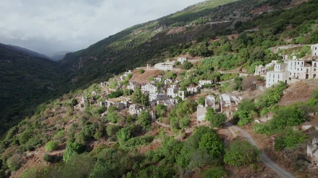 Aerial view flying over the ruins of Gairo Vecchio, an abandoned ghost town on a mountainside in Sardinia, Italy. Historic stone houses