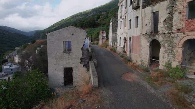 Drone view flying through the deserted streets of Gairo Vecchio, an old ghost town in Sardinia, Italy, showing ruined and abandoned houses