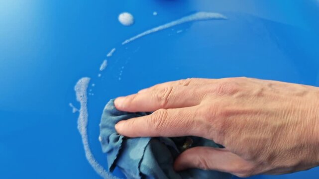 Cleaning a blue surface with a cloth while using soapy water for better results