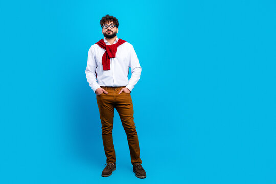 Confident young man in glasses and smart casual outfit posing against a bright blue background with a red sweater draped over his shoulders