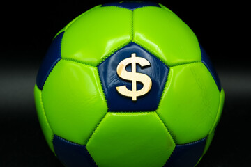 Obraz premium Dollar Symbol on a Green Soccer Ball. Gambling on the Worldwide Football Event, Close Up. Minimalism. Shallow depth of field.