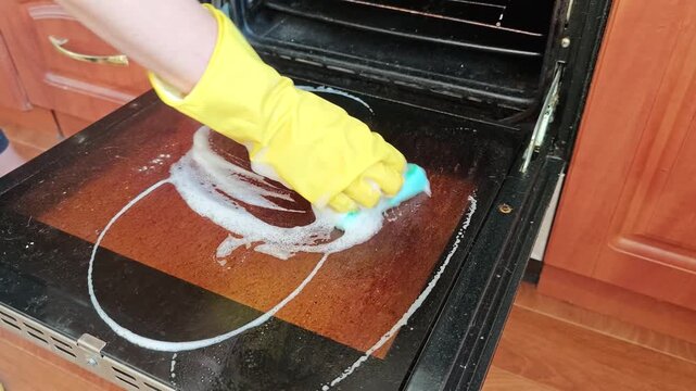 Cleaning the oven in a kitchen with a sponge and gloves during the day