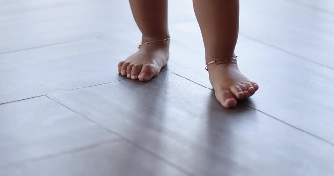 Toddler feet standing and stepping on indoor tile floor in natural light. Warm tone, symbolizing early walking, growth, and family lifestyle, close-up