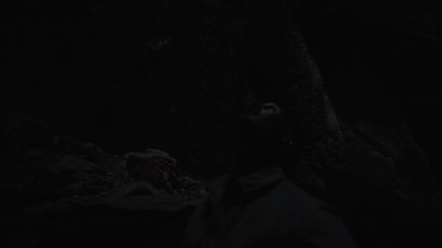 In the darkness a man is looking up from 90 metres down a sinkhole at the entrance as the light shines through.