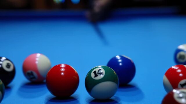 Billiard player smooth precise play with cue aiming at colorful balls opening spread on green pool table, man breaks pyramid of balls by hitting white ball with the cue, start game with his first shot