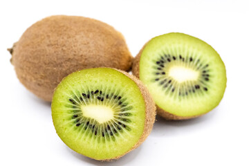 Fototapeta premium Fresh whole and halved kiwi fruit isolated on white background. Juicy green flesh fruit with tiny black seeds, diet concepts.