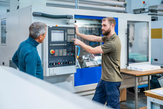 Two men discussing in a production hall with industrial machinery