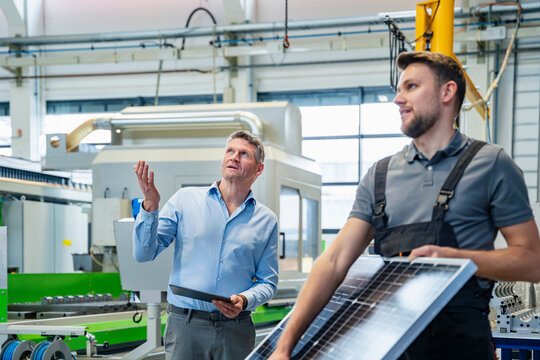Engineer and supervisor discussing solar panel production in factory