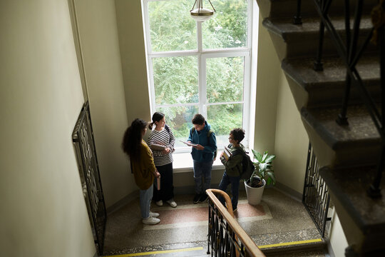 High angle view of teenage students waiting on a stairwell indoors